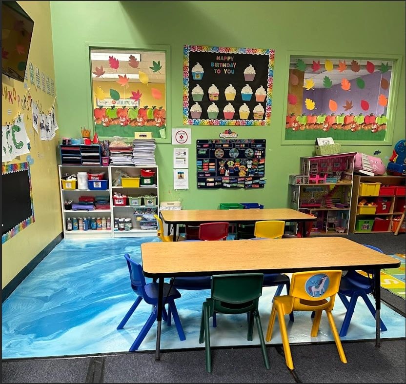 Bright lime green classroom with child-sized furniture, bulletin boards, and learning materials